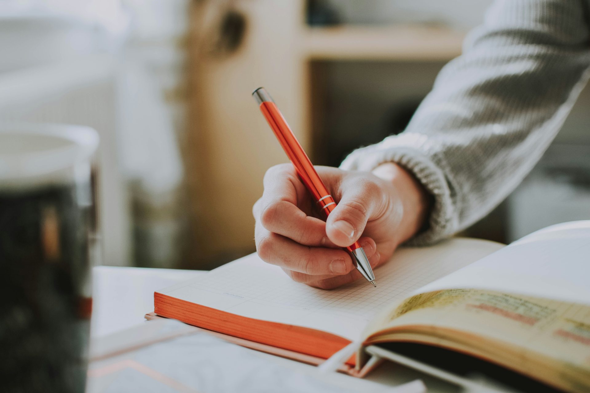 Person, die einen roten Stift hält, während sie in ein Buch schreibt