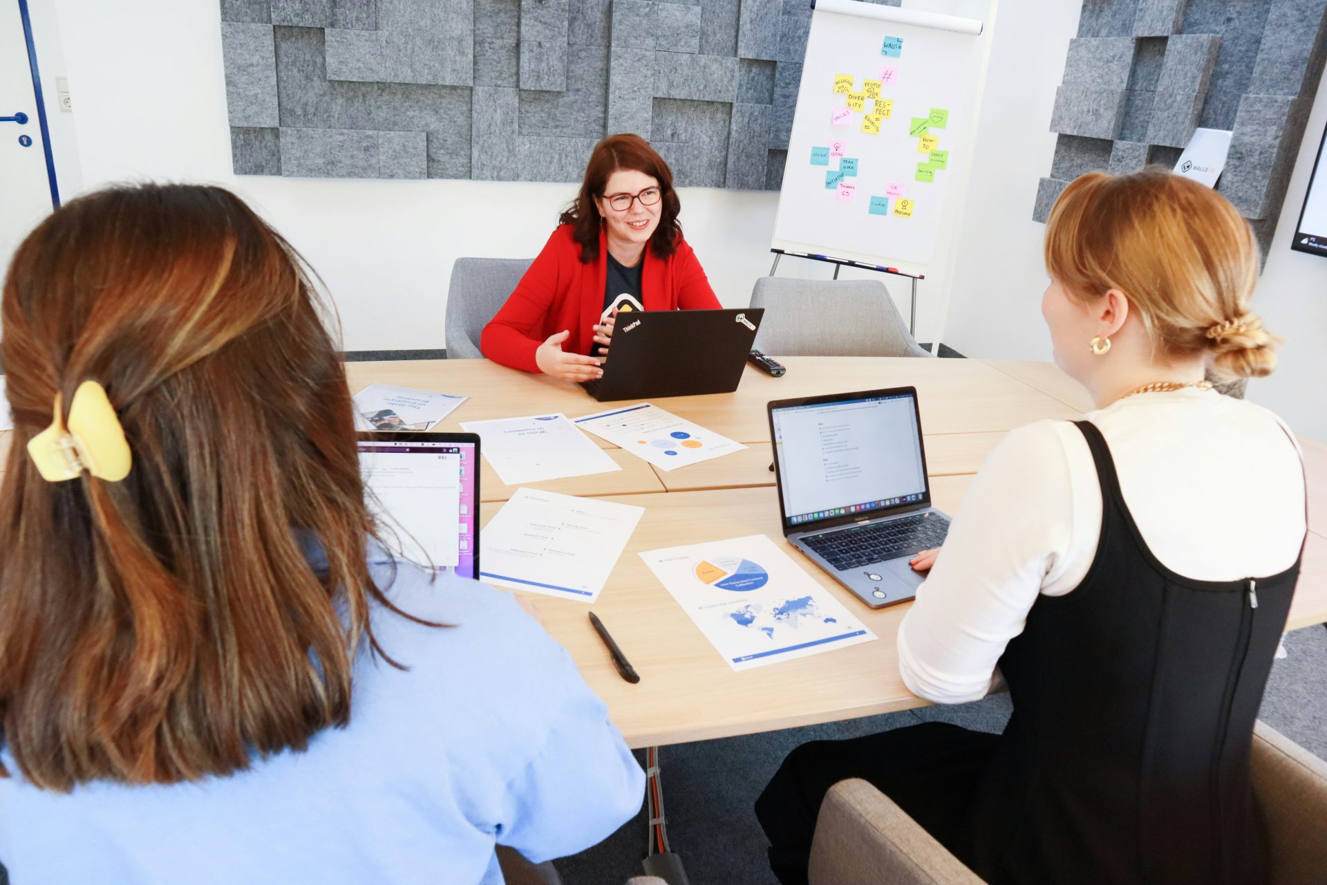 eine Gruppe von Menschen, die mit Laptops um einen Tisch herum sitzen